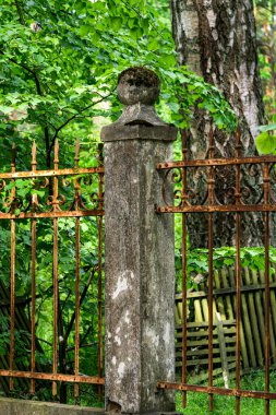 Beton sütunlar arasında dövülmüş, paslı bir çit var.