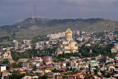 Tiflis işaretleri. Evler arasında dağ yamacında bir tapınak. Georgia 'yı geziyorum. Ekim ayının sonbaharında Tiflis manzarası. Georgia 'da şehir manzarası.