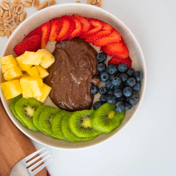 Yaban mersinli, çilekli, ananaslı ve çikolatalı fıstık ezmeli bir meyve tabağının en üst görüntüsü.