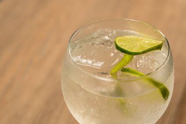 Cin tonik kokteylinin yakın planında ışığa karşı bir dilim limon..