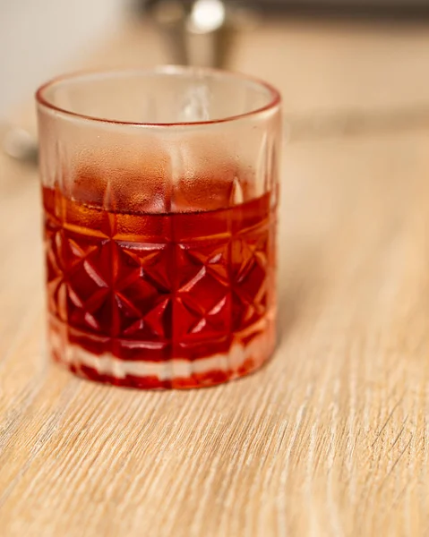 Ahşap bir yüzey üzerinde cam bir bardak içinde negroni kokteylinin ön görüntüsü.