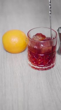 Kırmızı alkollü içecekle buz dolu bir bardaktan çıkan kaşık yavaş hareket ediyor.