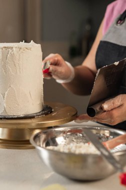 Pastayı tereyağlı kremayla süsleyen genç kadınların yakın plan fotoğrafları.