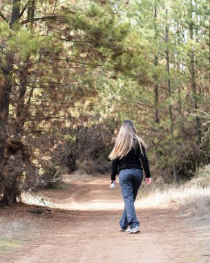 Ormanda yürüyen genç bir kadının dikey görünümü