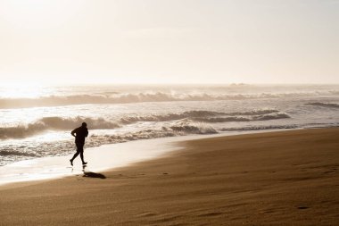 Sahilde koşan bir adamın silueti.