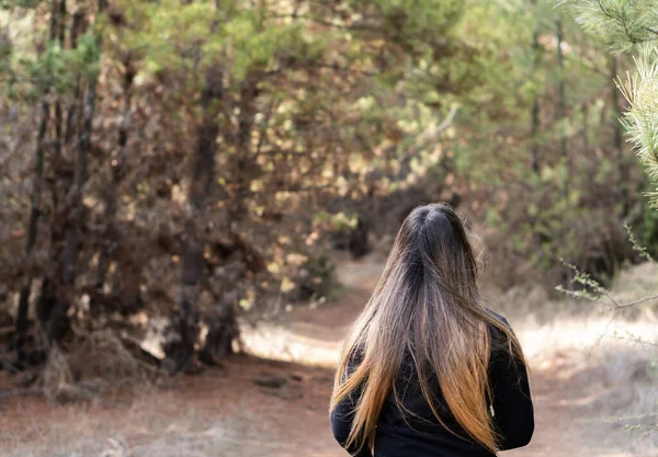 Genç bir kadın ormanda yürüyor.
