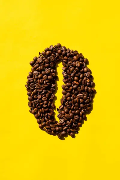Kahve çekirdeklerinin dikey üst görüntüsü, fasulye şeklinde ve sarı arkaplan..