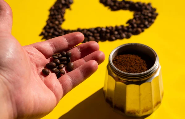 Kahve çekirdekleri ve sarı arkaplanda fasulyeli kahve demliği ile yakın plan.