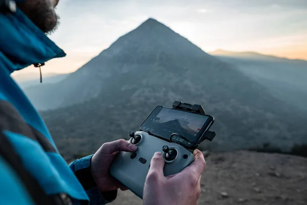 Yakın plan insansız hava aracı kontrolü. Arka planda günbatımı var.