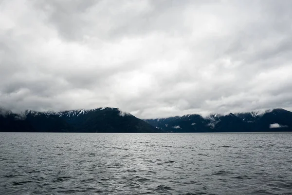 Panoramisch Uitzicht Besneeuwde Bergen Een Bewolkte Dag Een Meer Bodem — Stockfoto