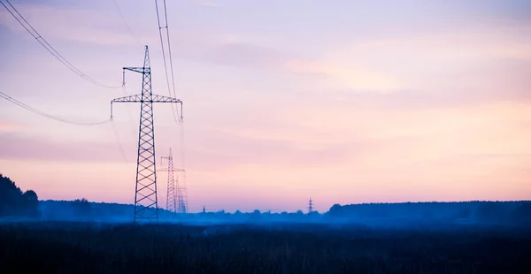 Yüksek gerilim elektrik hatları üzerinden günbatımı silüeti