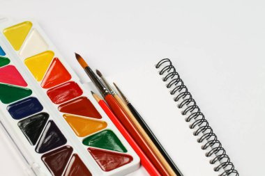 Bir dizi suluboya resim, defter ve beyaz bir masada fırçalar. Yaratılış.