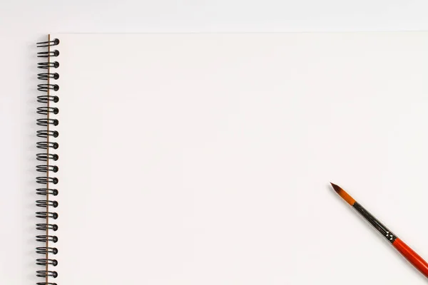 Çizim için bir defter ve beyaz bir masada bir fırça ile arka plan.
