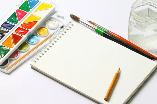 Bir dizi suluboya resim, defter ve beyaz bir masada fırçalar. Yaratılış.