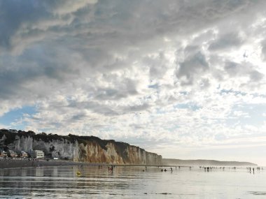 Panoramic view to white cliffs of Dieppe, ocean, silhouettes people during low tide of ocean