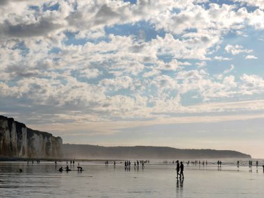 Panoramic view to white cliffs of Dieppe, ocean, silhouettes people during low tide of ocean
