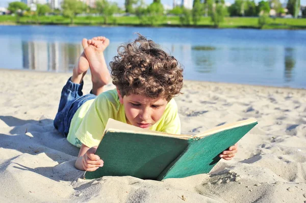 Lindo Niño Lee Libro Viejo Acuesta Arena Playa —  Fotos de Stock