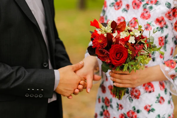 Closeup with couple holding hands and beautiful bouquet — Stock Photo, Image