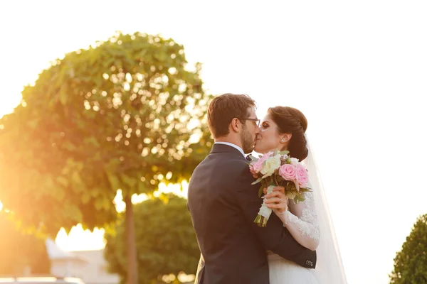 Noiva alegre e noivo com buquê abraçando ao ar livre — Fotografia de Stock