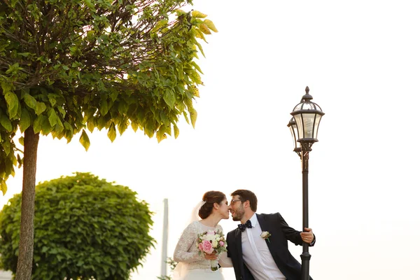 Joyful bride and groom with bouquet embracing outdoors — Stock Photo, Image
