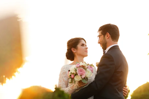 Blijde bruid en bruidegom met boeket omarmen buitenshuis — Stockfoto