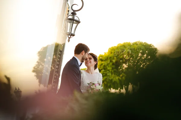 Joyful bride and groom with bouquet embracing outdoors — Stock Photo, Image