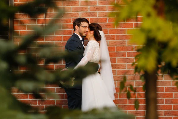 Joyful bride and groom with bouquet embracing outdoors — Stock Photo, Image