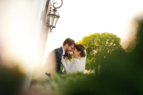 Freudige Braut und Bräutigam mit Blumenstrauß, die sich im Freien umarmen — Stockfoto
