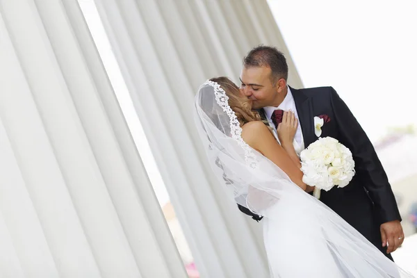 Piękne suknie ślubne para obejmując w pobliżu kolumny — Zdjęcie stockowe