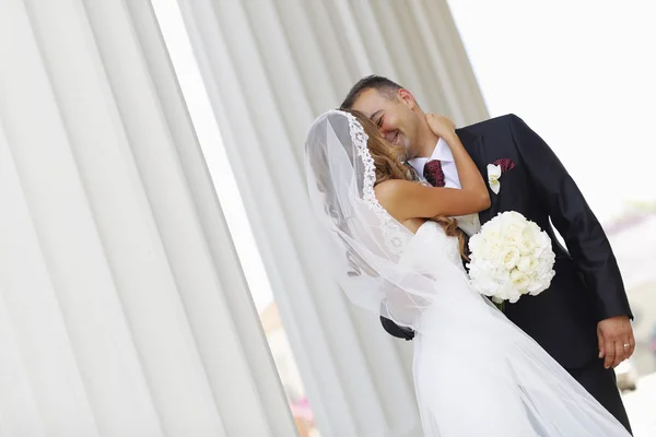 Beautiful bridal couple embracing near columns — Stock Photo, Image