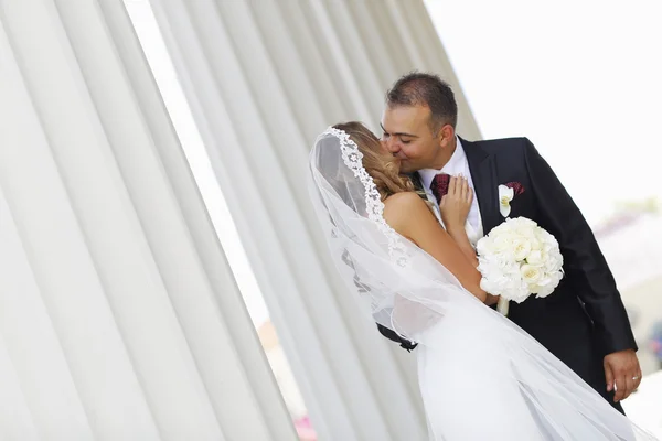 Beautiful bridal couple embracing near columns Stock Photo