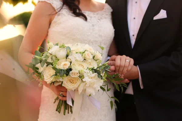 Bruden och brudgummen hålla hand med brudbukett — Stockfoto