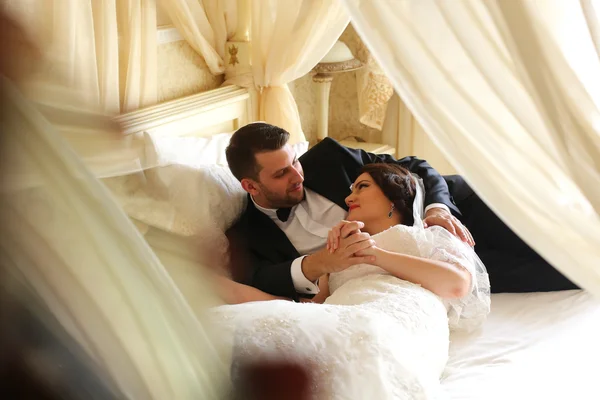 Noiva e noivo abraçando na cama do quarto do hotel — Fotografia de Stock