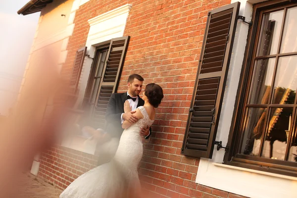 Beautiful bride and groom embracing near house — Stock Photo, Image