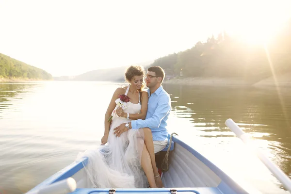 Beautiful bridal couple embracing in boat — Stock Photo, Image