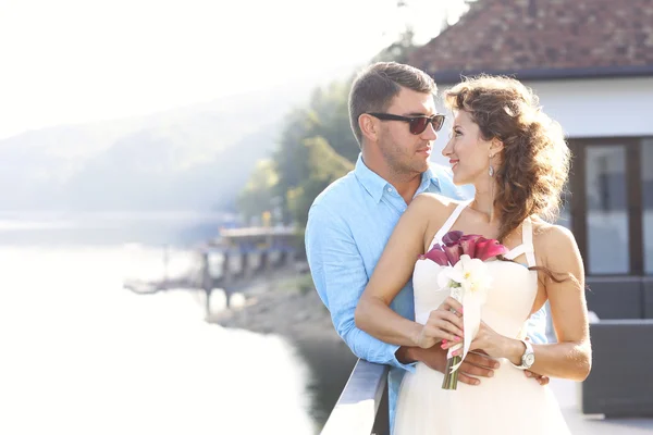 Bruid en bruidegom omarmen in de buurt van lake — Stockfoto