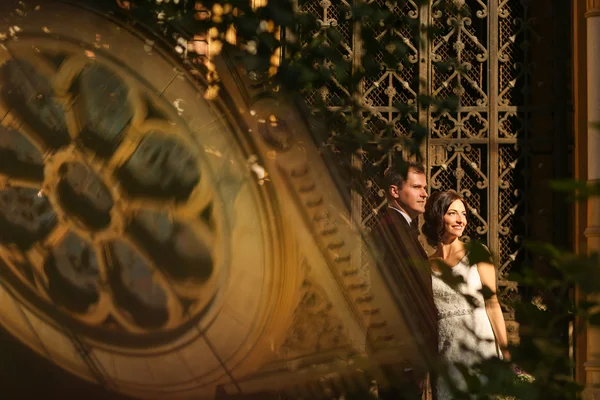 Lovely groom and bride kissing and holding outside, with a church reflection — Stock Photo, Image