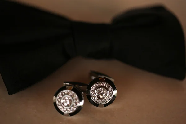 Black bow tie and two earrings on the table — Stock Photo, Image