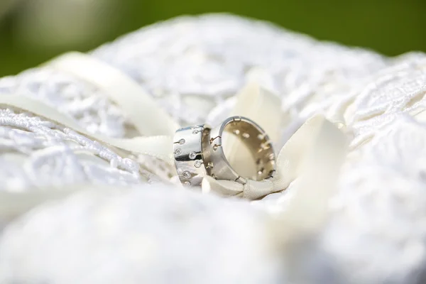 Два серебряных обручальных кольца на белой подушке — стоковое фото