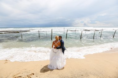 Gelin ve damat sahilde poz veriyorlar.