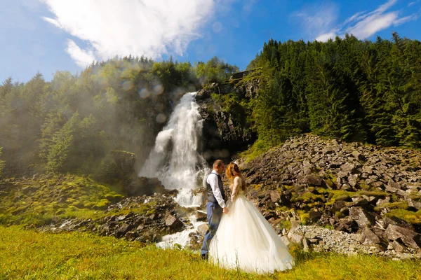 Noiva e noivo posando ao lado de uma cachoeira — Fotografia de Stock