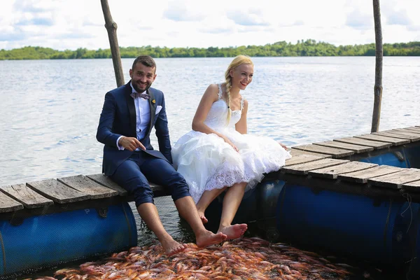 Mariée et marié assis avec leurs pieds dans l'eau — Photo