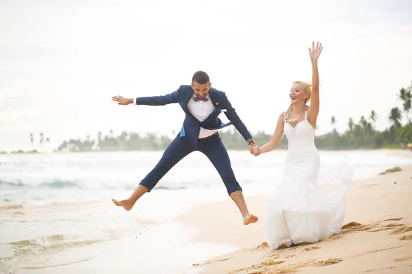 Nevěsta a ženich hraje na pláži — Stock fotografie