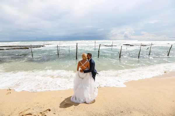 Brud och brudgum poserar på stranden — Stockfoto