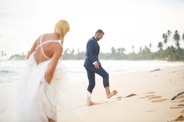 Bruden och brudgummen spelar på stranden — Stockfoto