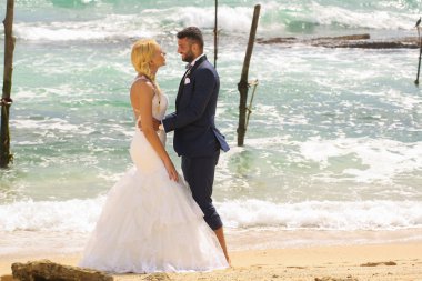 Gelin ve damat sahilde poz veriyorlar.