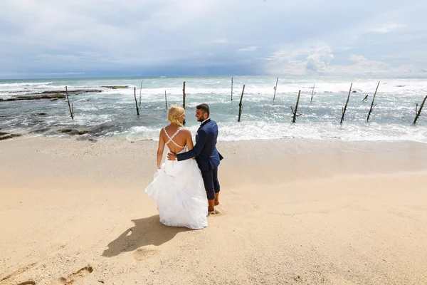 Brud och brudgum poserar på stranden — Stockfoto