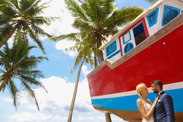 Novia y novio besándose en la playa cerca de un barco de madera —  Fotos de Stock