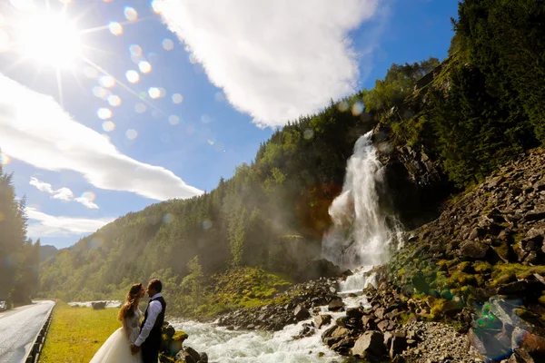 Nevěsta a ženich pózuje u vodopádu — Stock fotografie