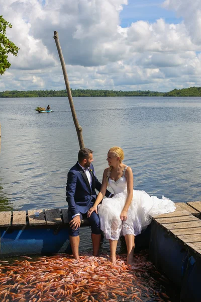 Mariée et marié assis avec leurs pieds dans l'eau — Photo
